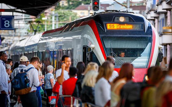 Treno regionale e viaggiatori che aspettano sul binario alla stazione di Losanna.